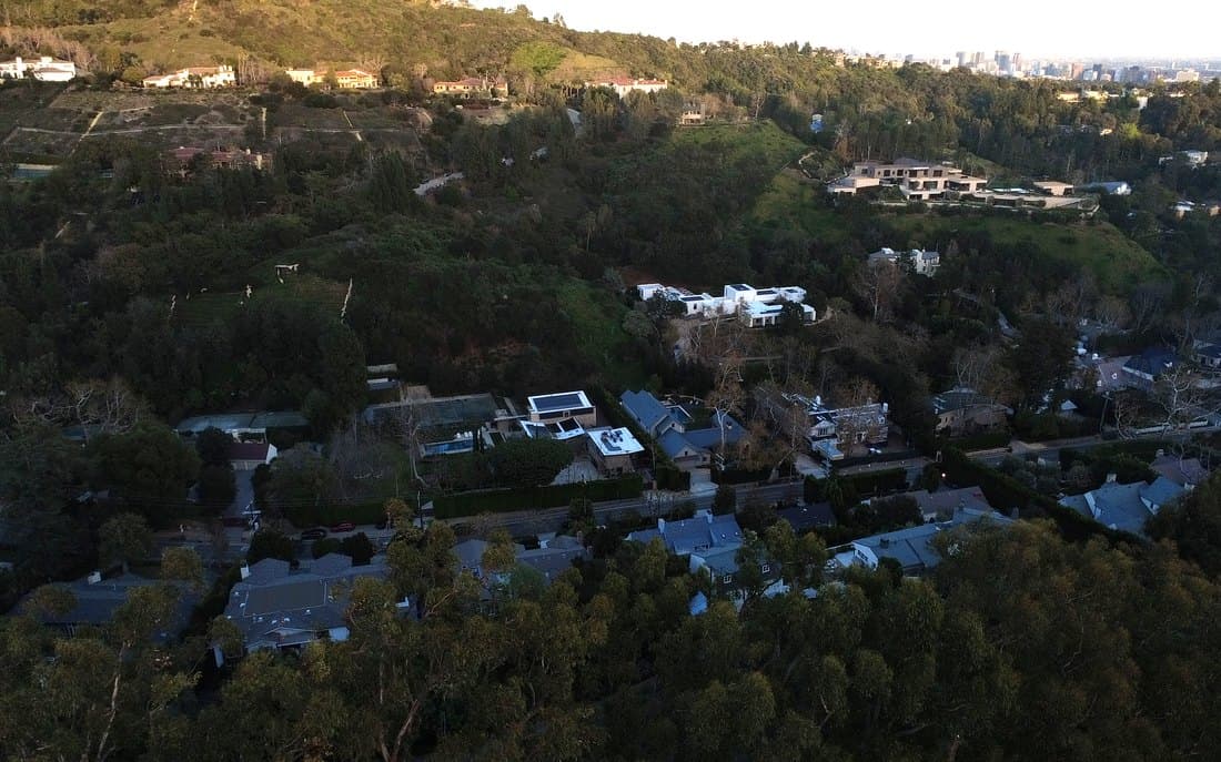A canyon climbing toward houses on the ridge above it