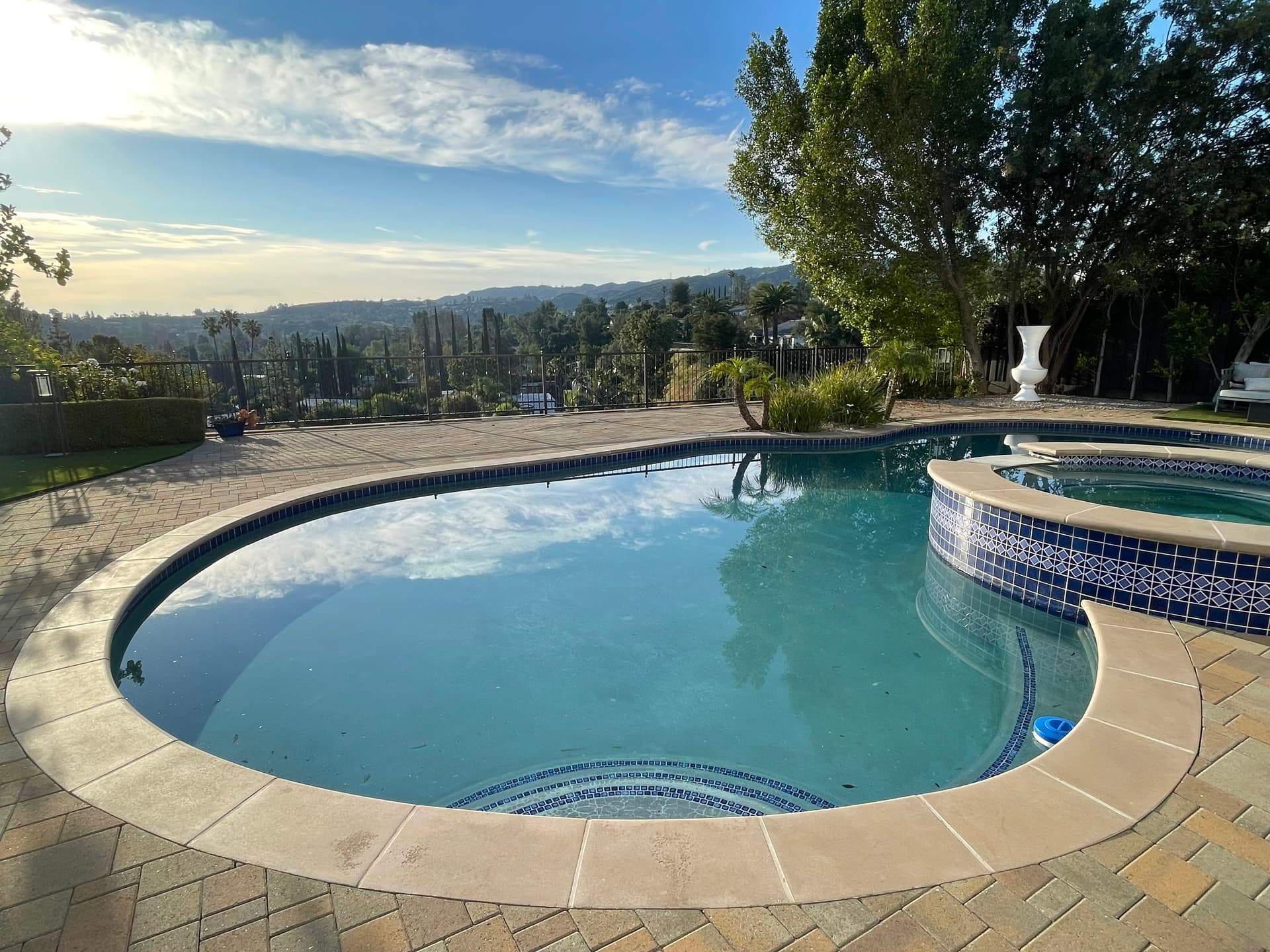 A backyard swimming pool and spa overlooking a hillside at dusk, serving as the system’s secondary water source.